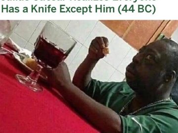 Удивленный негр за столом мем